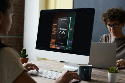 Two people working at a desk with computer monitors and books.